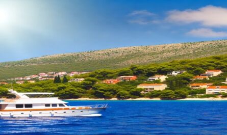 A beautiful boat charter glides over the clear blue waters of the Adriatic Sea, with Croatia's picturesque coastline featuring red-roofed buildings and lush green hills under a sunny sky