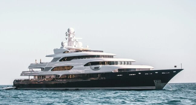 A sleek luxury yacht anchored calmly on open blue sea under a clear bright sky