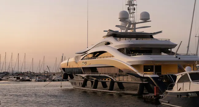 A stylish luxury yacht docked at a marina during a peaceful sunset with other boats nearby