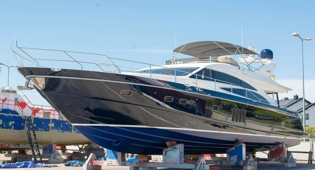A sleek black and white luxury yacht positioned on dry dock for maintenance and repairs