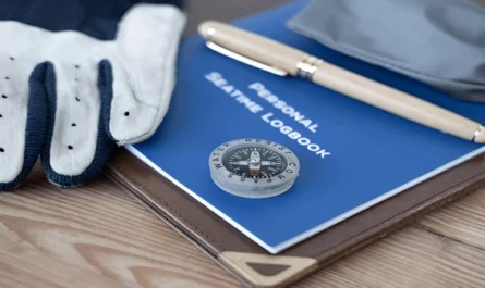 Detailed view of a sailor's logbook about yacht career opportunities, compass and gloves on wooden desk