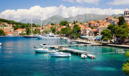 Weiße Segelyacht vor der kroatischen Küste mit Altstadt, Hügeln und blauem Himmel im Hintergrund