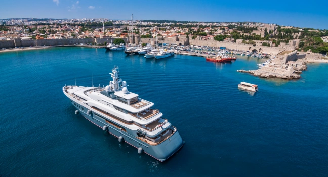 A luxury yacht anchored near a historic coastal city with vibrant marina views at yacht charter Athens