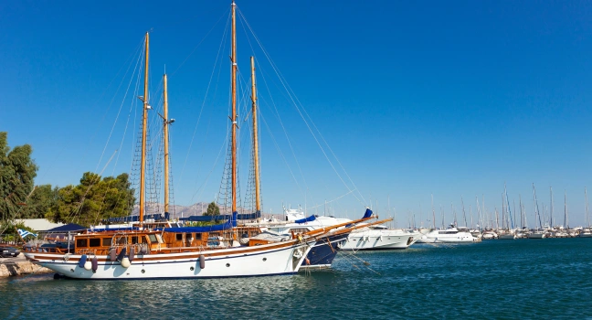 A wooden gulet docked at a Mediterranean marina with calm waters
