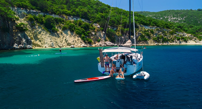 A group of people relaxing on a sailing yacht in a turquoise bay near cliffs