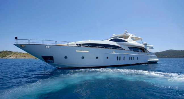 A luxurious white yacht cruising through clear blue waters near an island