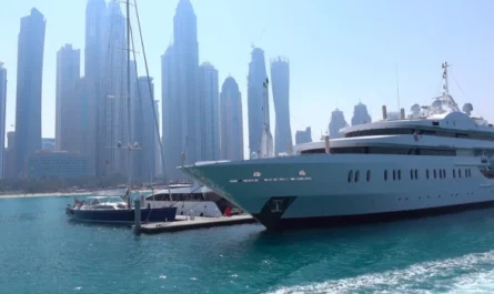 A large luxury yacht moored at Dubai Marina with modern skyscrapers in the background