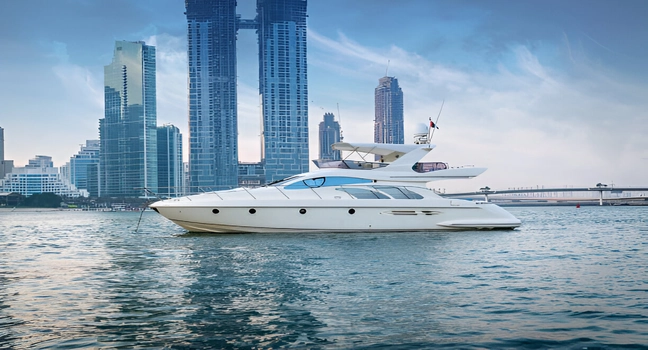 A sleek white luxury yacht anchored calmly with Dubai’s modern skyline behind