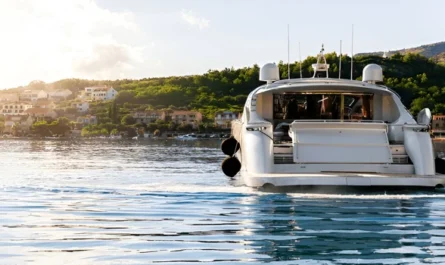 White motor yacht departs a scenic coastal town surrounded by greenery yacht charter capri