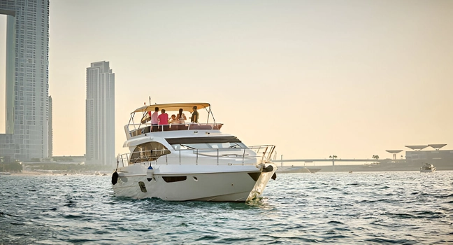 A group of people enjoying a sunset yacht cruise near the Dubai skyline