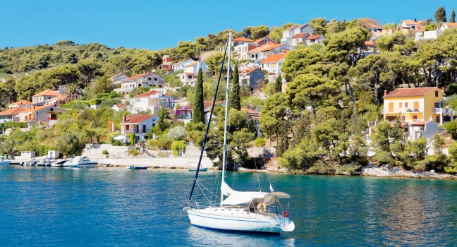 Sailing Yacht in Front of Colorful Houses A white sailing yacht anchored by colorful hillside houses in Croatia