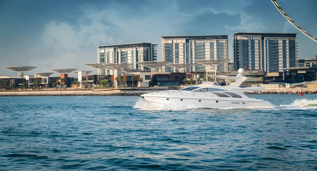  A modern white yacht speeding past luxury residences along Dubai’s waterfront