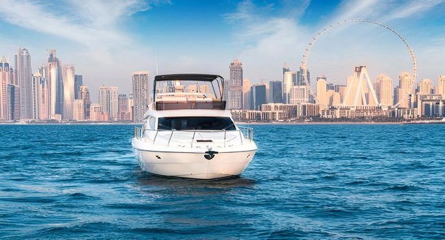 A front view of a white yacht cruising with Ain Dubai and skyline in the distance