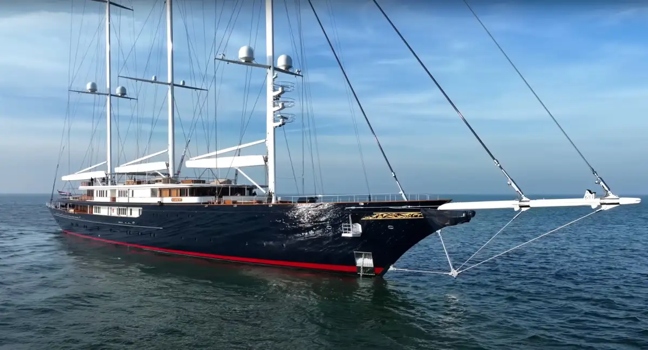 Die Luxussegelyacht „Koru“ von Jeff Bezos liegt ruhig im Wasser und zeigt ihre elegante Linienführung mit dunklem Rumpf, drei Masten und edlen Details – ein Ort für außergewöhnliche Erlebnisse und höchsten Komfort an Bord