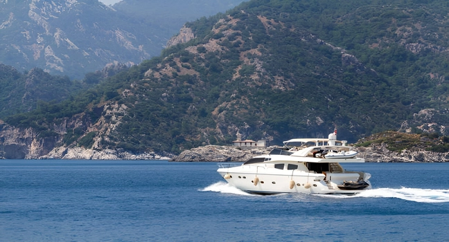 A motor yacht cruising close to the rugged and green Turkish coastline