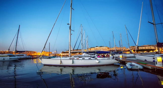 Sailing yachts resting at a peaceful marina under blue hour twilight lighting