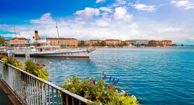 Blick über den Genfersee mit Uferpromenade, Pflanzen und historischem Schiff – regionale Atmosphäre rund um den Bellerive Yacht Club