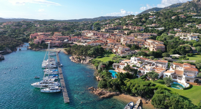 Blick auf einen Yachthafen mit Segelbooten entlang einer Küste – Symbol für die Wahl der richtigen Bootsgröße je nach Route