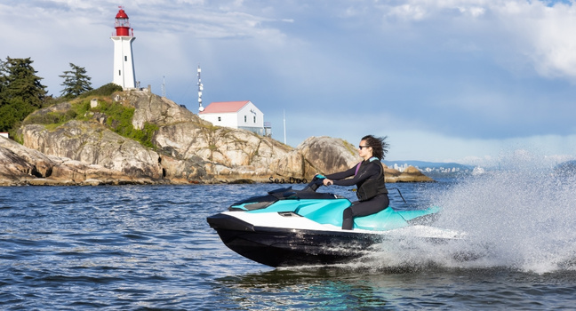 Frau fährt auf einem Sea-Doo Jet Ski entlang eines Leuchtturms über das Meer