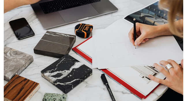 Arbeitsplatz mit Materialmustern und Skizze eines Designs auf einem Tisch