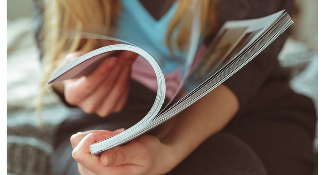 Person blättert in einem Yacht Magazin und liest die Inhalte durch