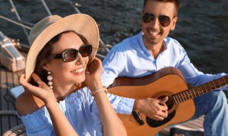 Paar spielt Gitarre und entspannt auf einer Yacht – Stimmung eines Musikfestival-Wochenendes auf dem Wasser