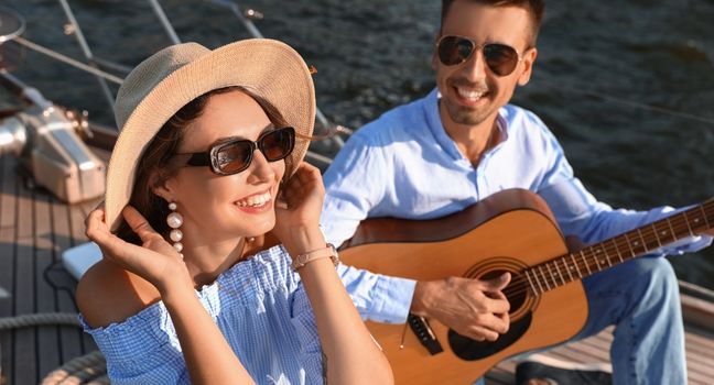 Paar spielt Gitarre und entspannt auf einer Yacht – Stimmung eines Musikfestival-Wochenendes auf dem Wasser