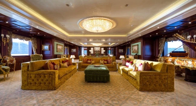Luxuriöser Salon der Black Pearl Yacht mit goldenen Sofas, Kristallleuchter und edlem Interieur – Beispiel für Design und technische Meisterleistung.