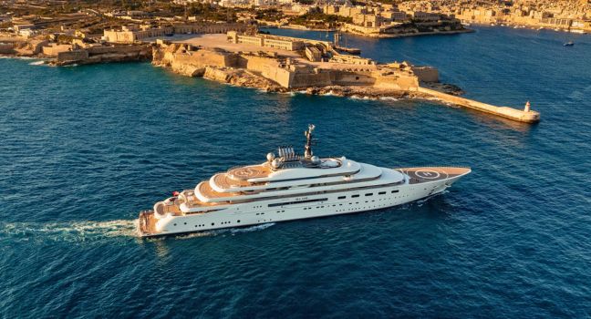 Luxusyacht der Lürssen Werft auf See vor historischer Küstenstadt, Symbol für Tradition und weltweite Präsenz