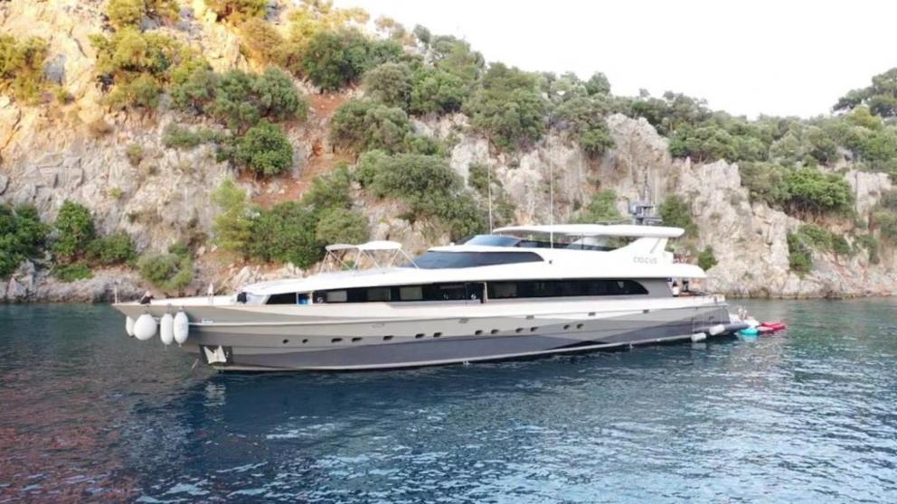 The luxury yacht creates a whole image with nature as it moves close to the tree-lined rocks.