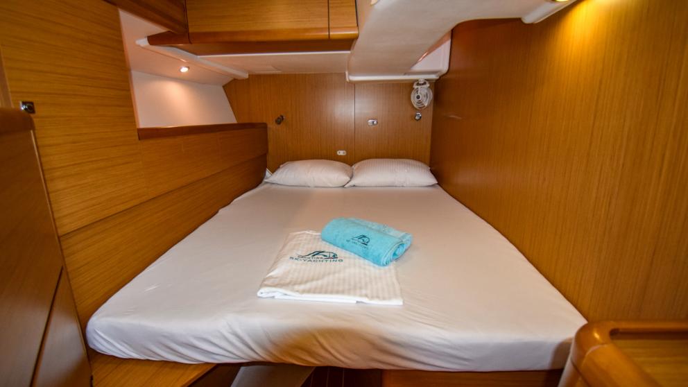 Double bed in the cabin with bed linen on the yacht. You can see the ceiling lighting