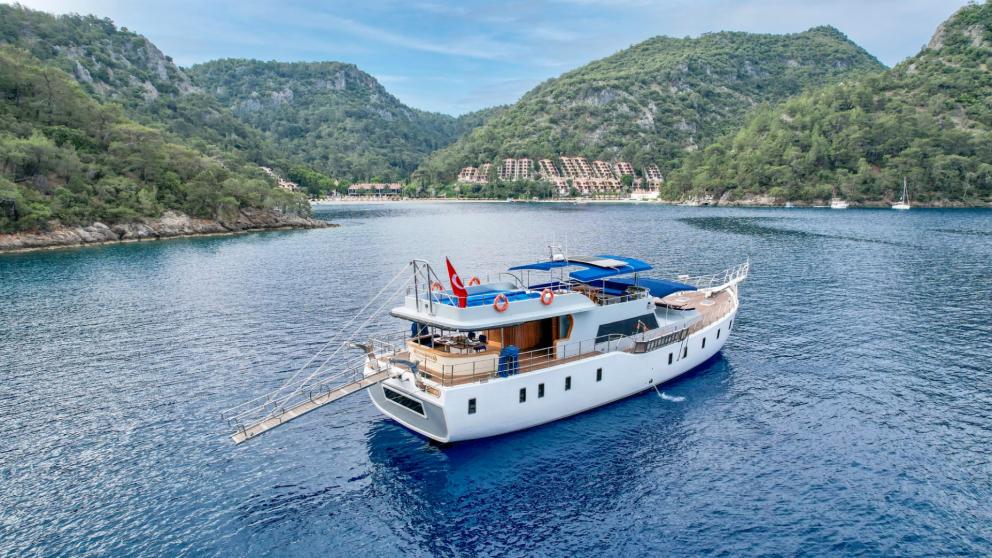 The 6-cabin gulet Enjoy Life is anchored in a picturesque bay surrounded by green hills.