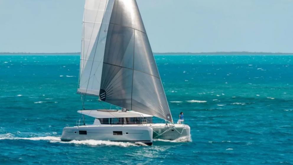 The luxury catamaran Fujin is cruising with sails unfurled.