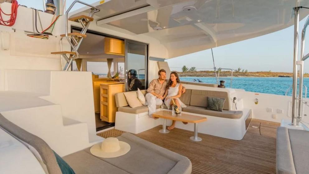 A couple sits on the deck of the catamaran Kairos.