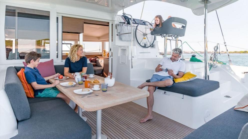 Children and their parents have a snack on the deck of the catamaran Shima.