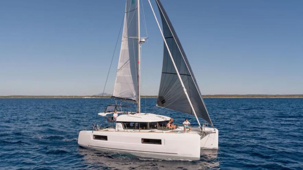 The catamaran Turtle is sailing with its sails unfurled, guests are enjoying the journey.