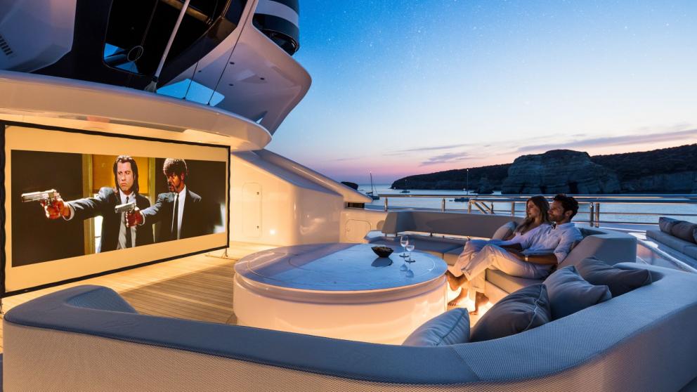 Outdoor cinema on the Opari yacht with a large screen, comfortable seating, and a sunset view.