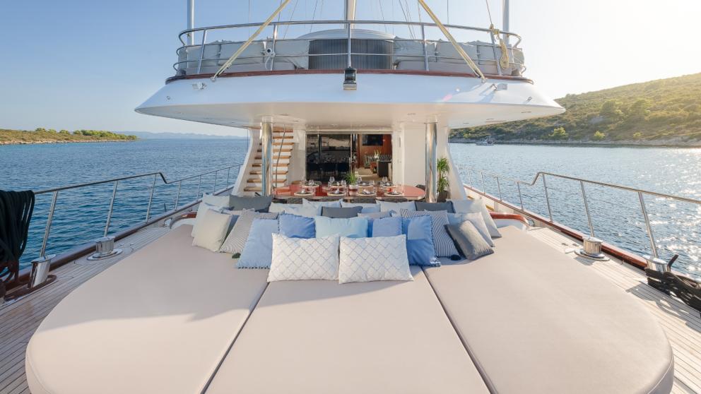 The luxury yacht offers generous sun loungers with decorative cushions on the rear deck.