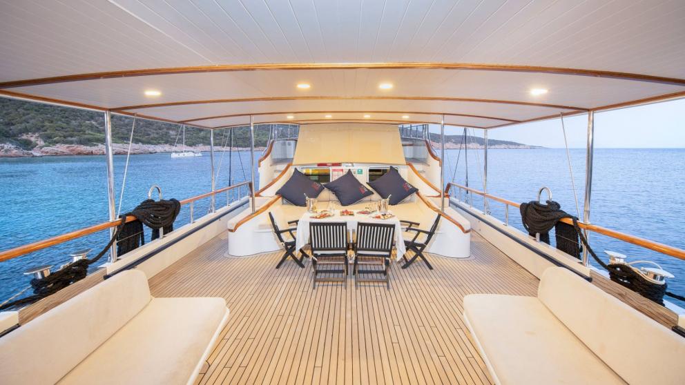 Lounge area on the deck of the gulet Oguz Bey with cosy sofas and a dining table.
