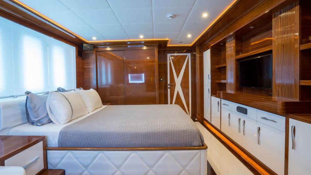 Elegant cabin of Anima Maris with wood paneling, large bed, and TV, perfect for luxurious relaxation.