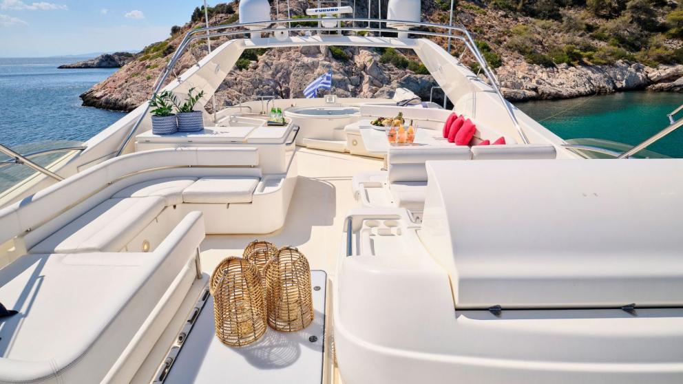 Comfortable seating area on the flybridge of a motor yacht with views of rocky coastline and turquoise water