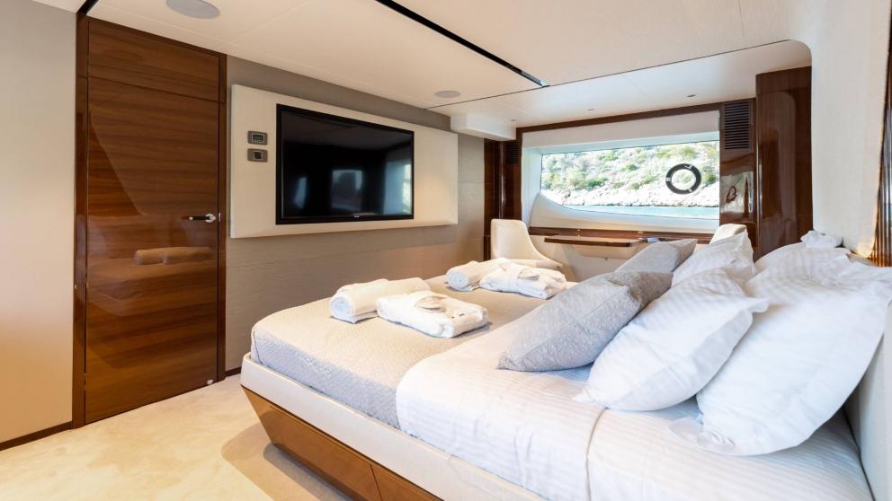 Stylish bedroom with large window and TV on a yacht.
