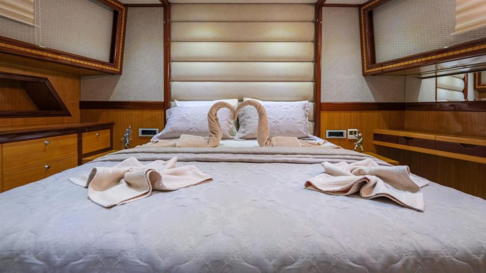 Close-up of a cozy double bed with decorative towels in the cabin.