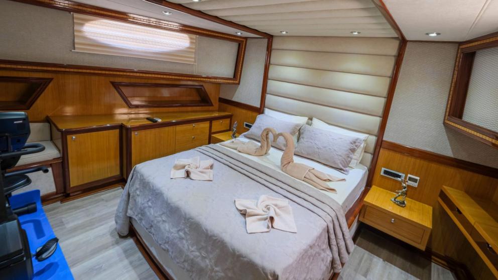 Comfortable cabin with a double bed, decorative towels, and storage space on the gulet.
