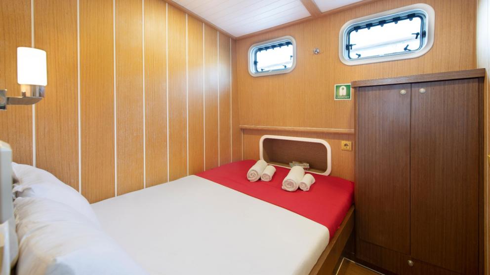 A well-equipped cabin with a comfortable double bed and natural light.