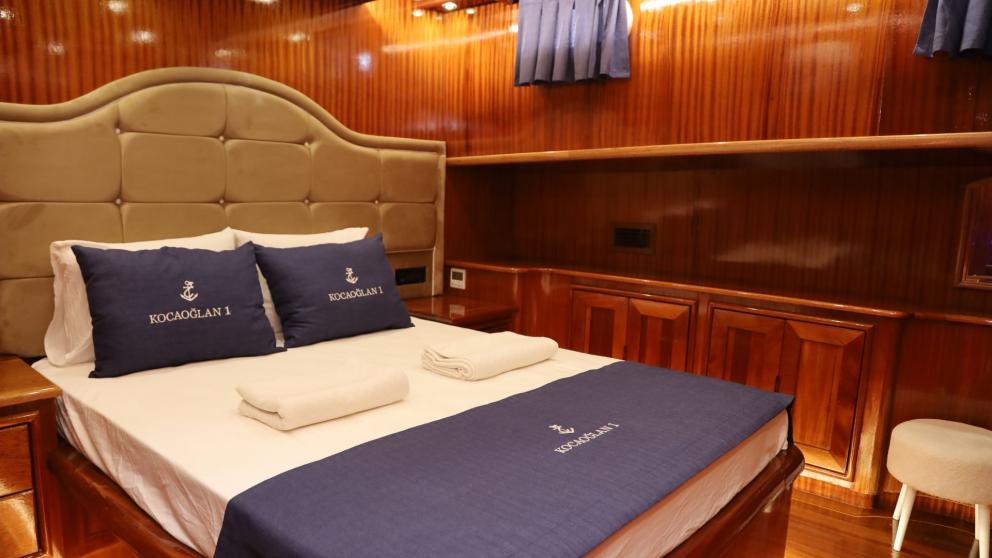 Yacht cabin with double bed and wood panelling.