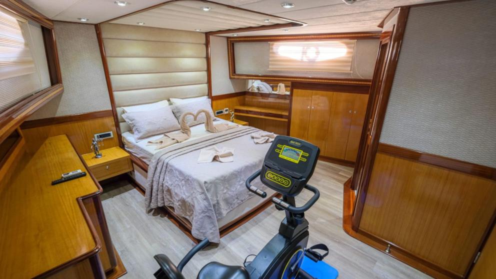 Spacious cabin with a double bed, fitness equipment, and decorative towels.