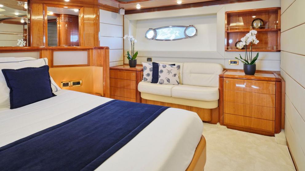 Elegant cabin with a large bed, stylish decor, and cozy seating area on a yacht