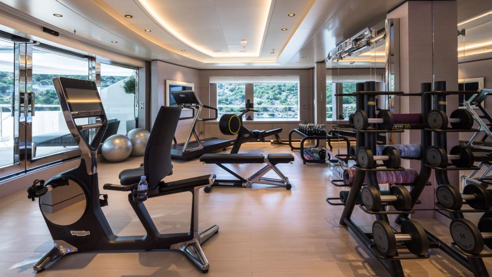 Gym on the Opari yacht with modern equipment, large windows, and sea views.