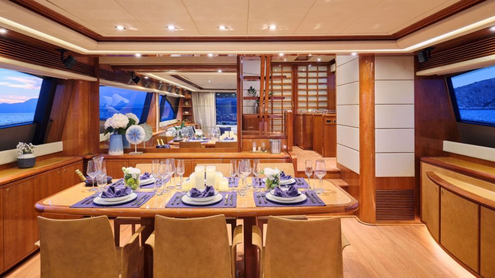 Luxuriously set dining table inside a yacht with large windows and sea view